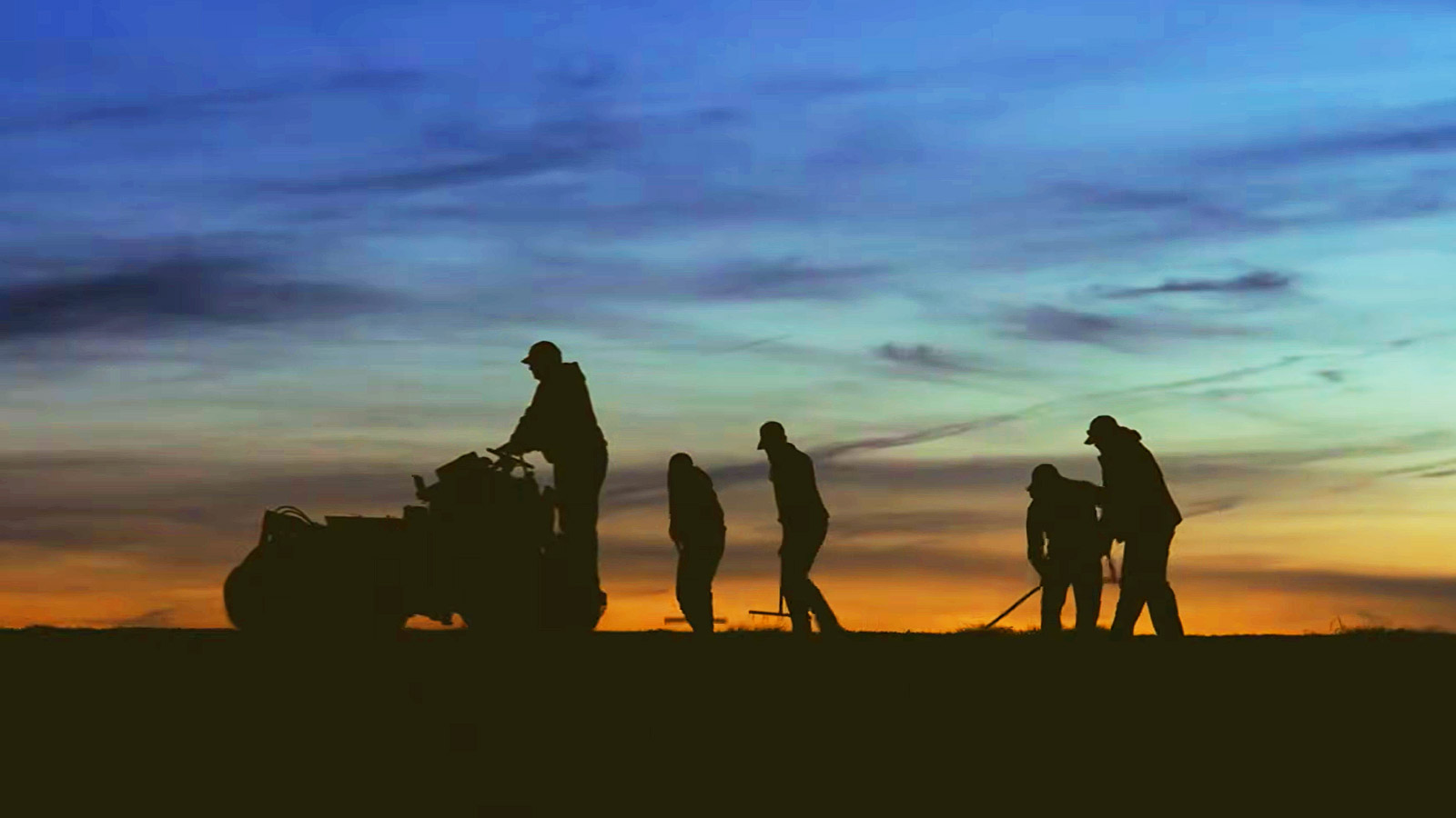 Carolina Green crew working on an athletic field at sunset
